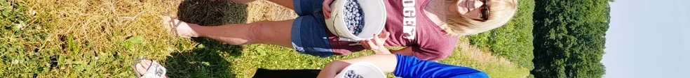 People holding up buckets of blueberries