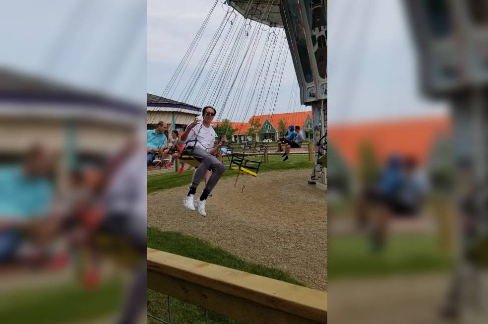 A woman swinging on a ride in a park wearing white