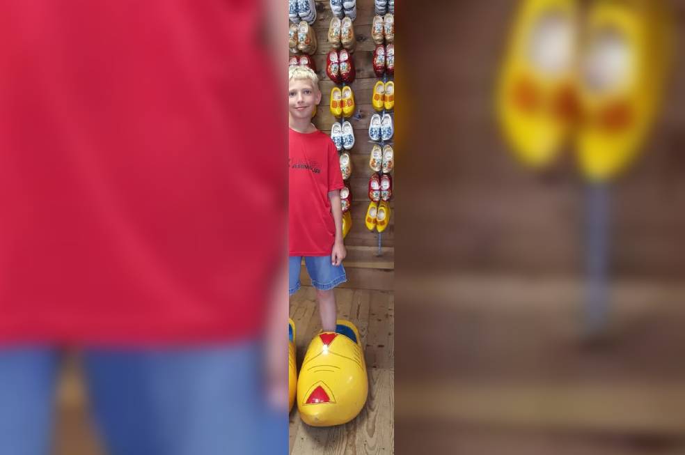 A small boy wearing a giant yellow show and smiling